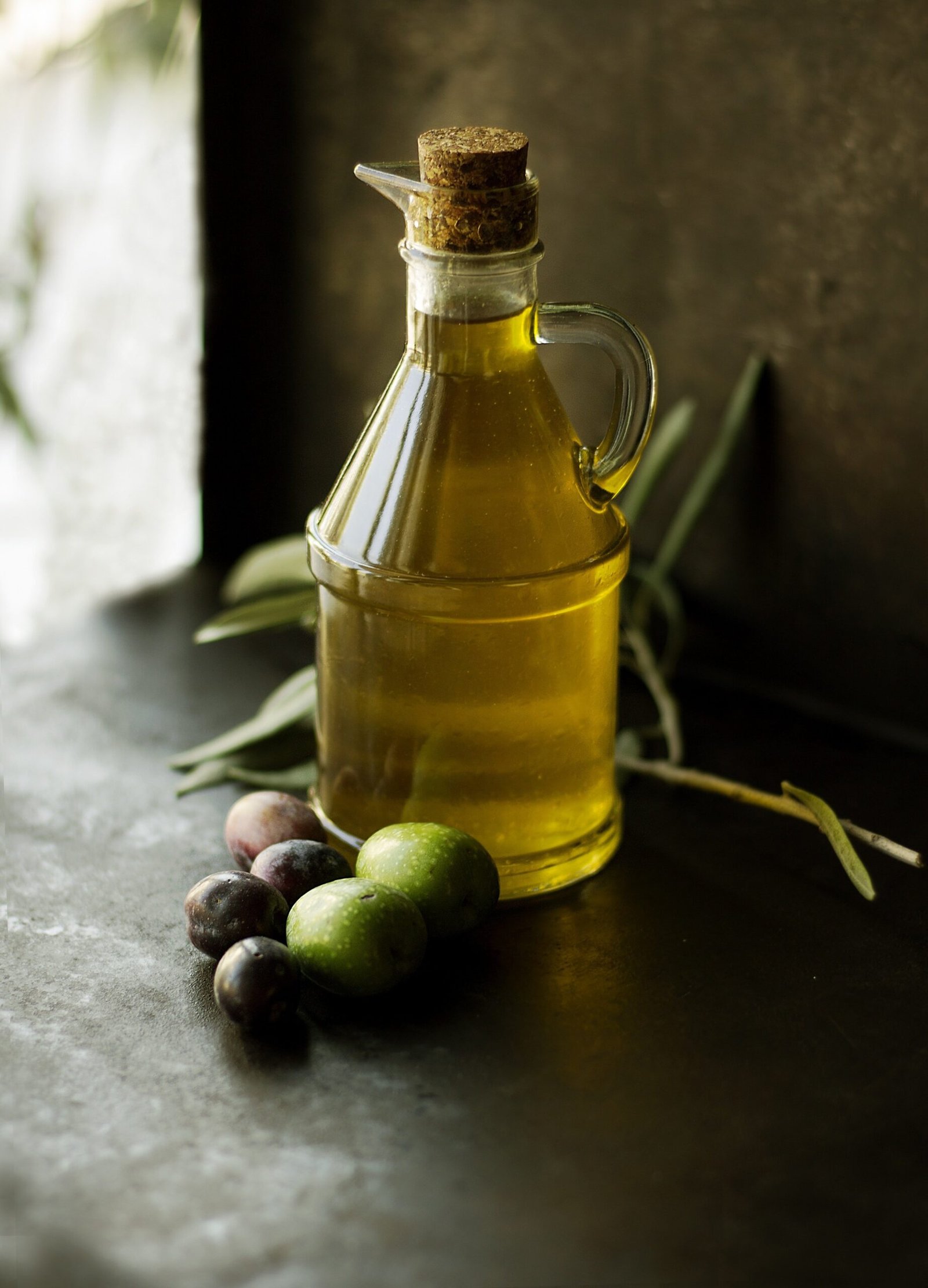 Bottiglia di olio EVO con olive su tavolo: guida filtrato vs non filtrato.